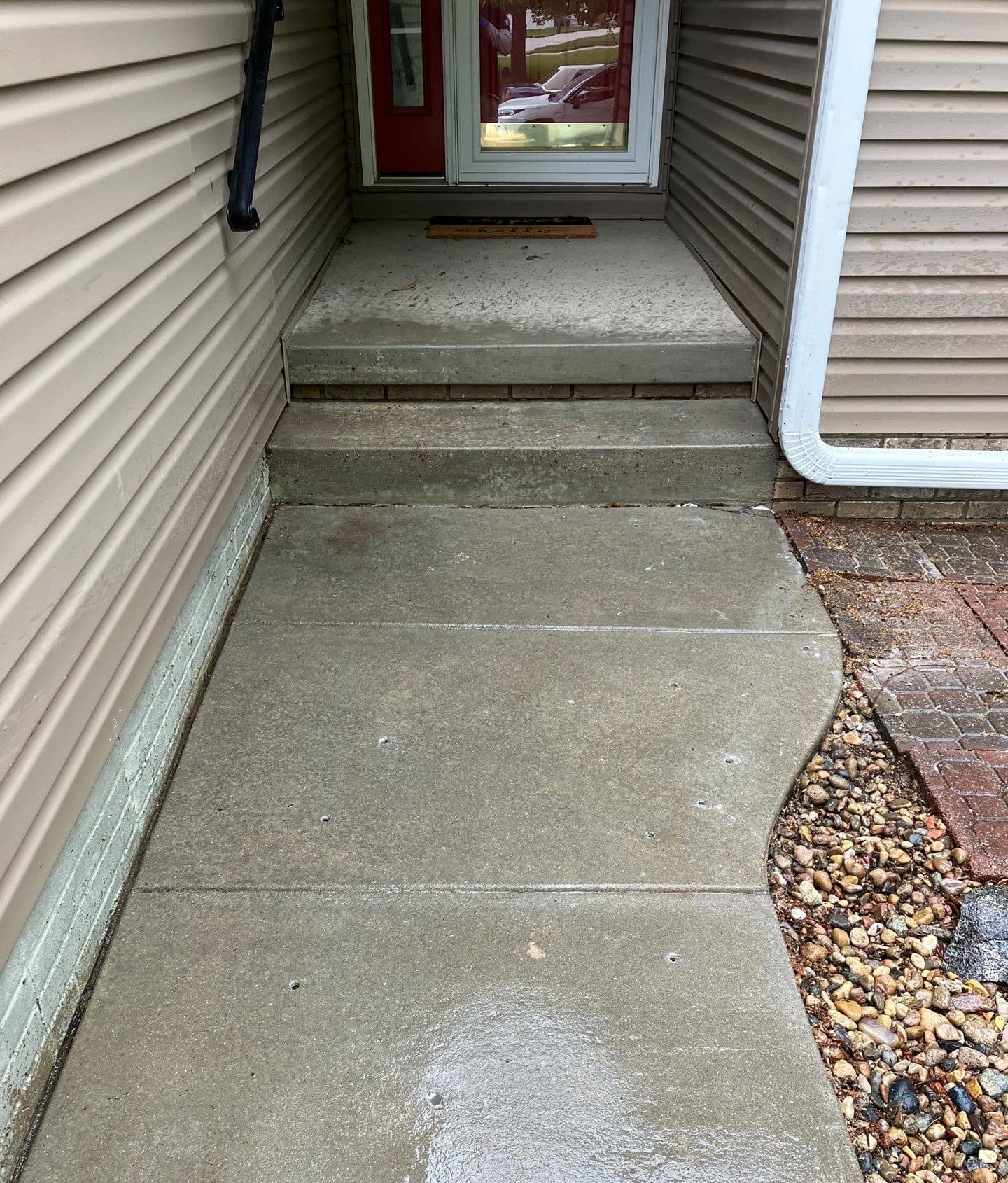 Concrete front steps and the walkway below them, with small injection holes drilled in the walkway slab.