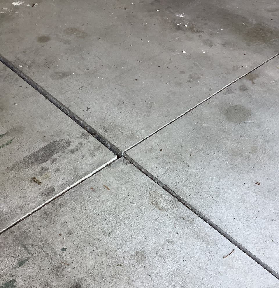 Completed concrete flatwork installation showing four concrete slabs with finished joints and sealant between panels.