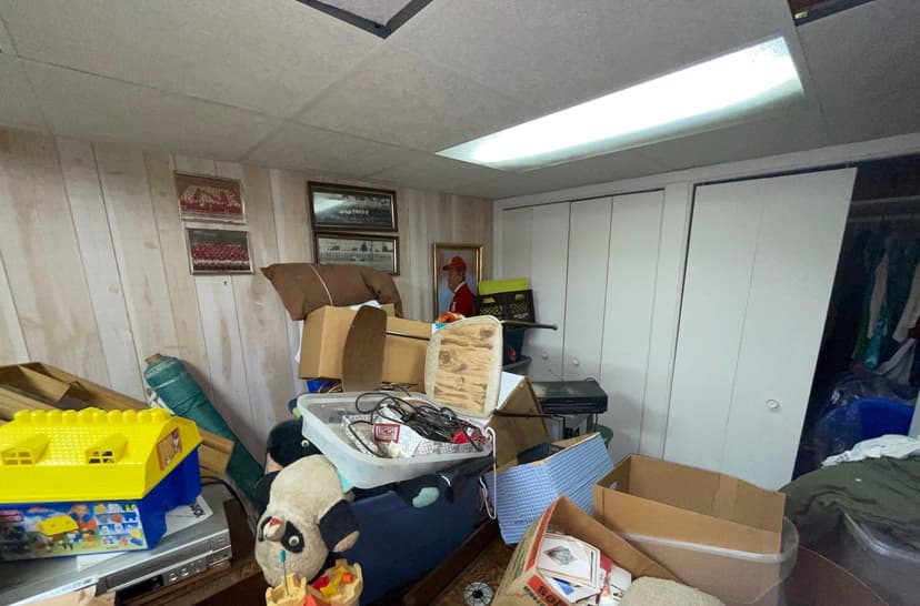 Epp Foundation Repair assessing flood damage in a cluttered basement with water stains in Lincoln, Nebraska.