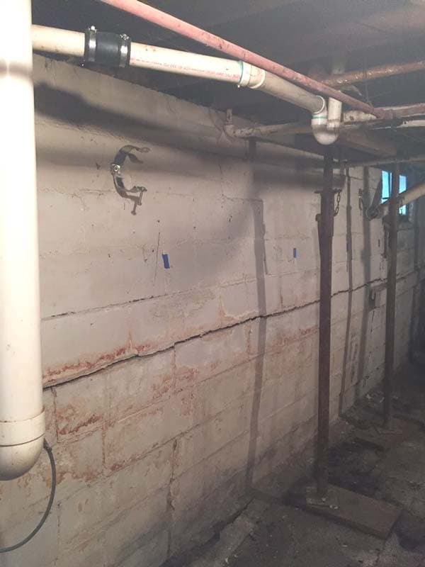 Epp Foundation Repair inspecting a horizontal crack and efflorescence on a concrete block basement wall.