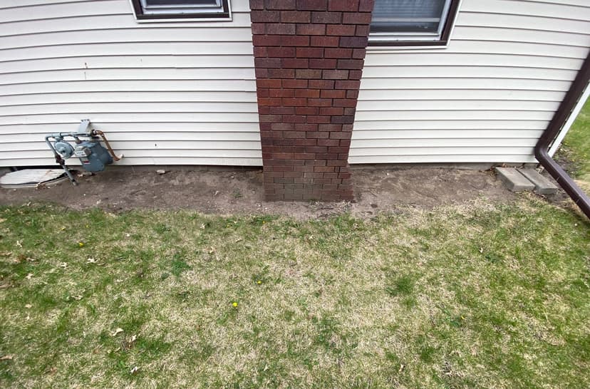 Epp Foundation Repair inspecting an exterior bowing brick chimney and exposed foundation with a leaning gas meter in Seward,