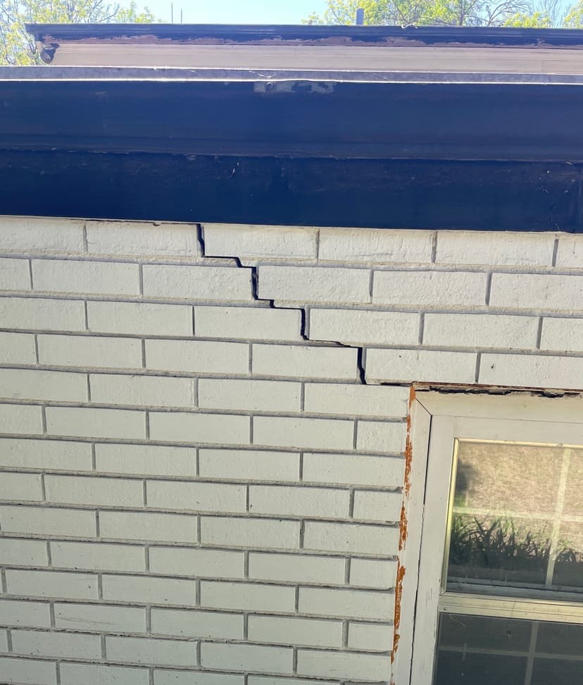 Epp Foundation Repair inspecting a stair-step crack in a white brick exterior wall in Lincoln, NE.
