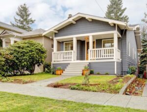 Blue grey smal craftsman style house with white porch.