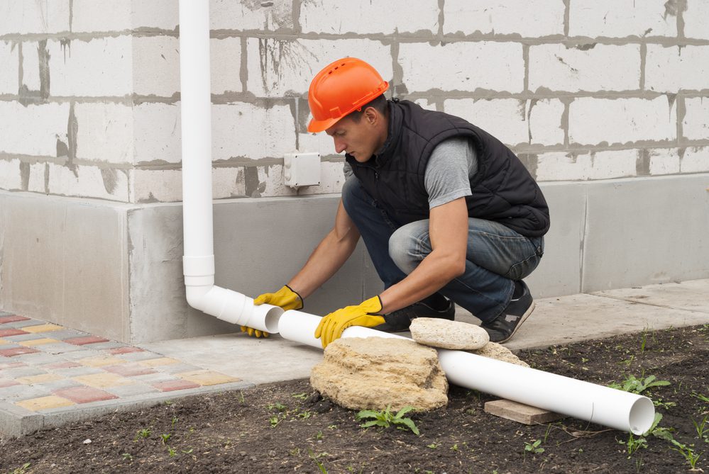 man installing a downspout extension
