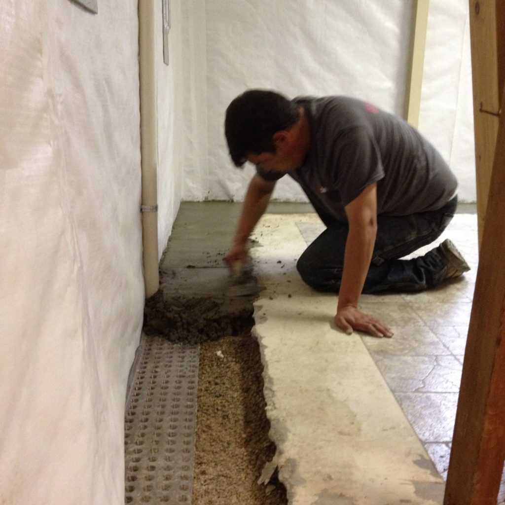 Photo of a man installing drain tile to achieve ideal basement humidity