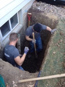 Two men installing a basement egress window